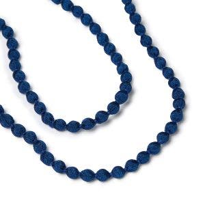 Close up detail of dark blue beads sewn together to form a long necklace.