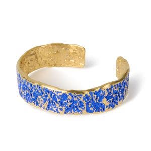 A wide gold-plated cuff bracelet with a blue texture design