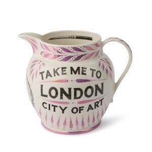 Decorative ceramic jug featuring hand-painted vintage black and white illustration of a paintbrush along the inner rim, with "Take me to London, City of Art" text on the exterior accented with pink leaf designs.