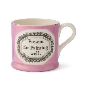 A lustre pink mug with 2 "Present for Painting well." written in black in the centre.