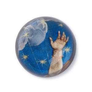 A painted hand design in a dome paperweight.